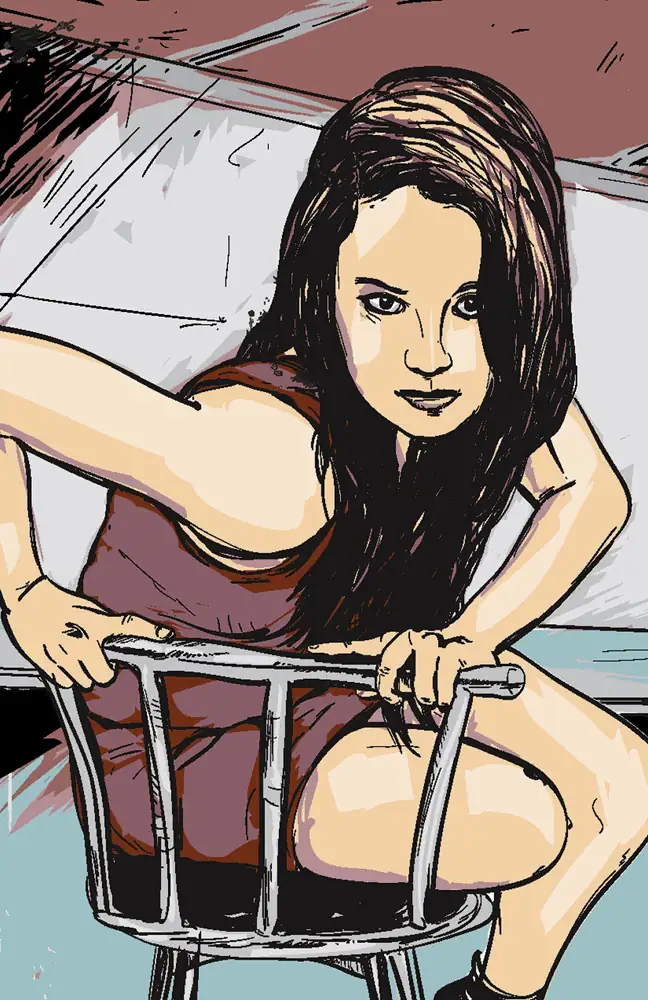 A woman with long dark hair sitting on a metal chair, leaning forward with an intense expression.