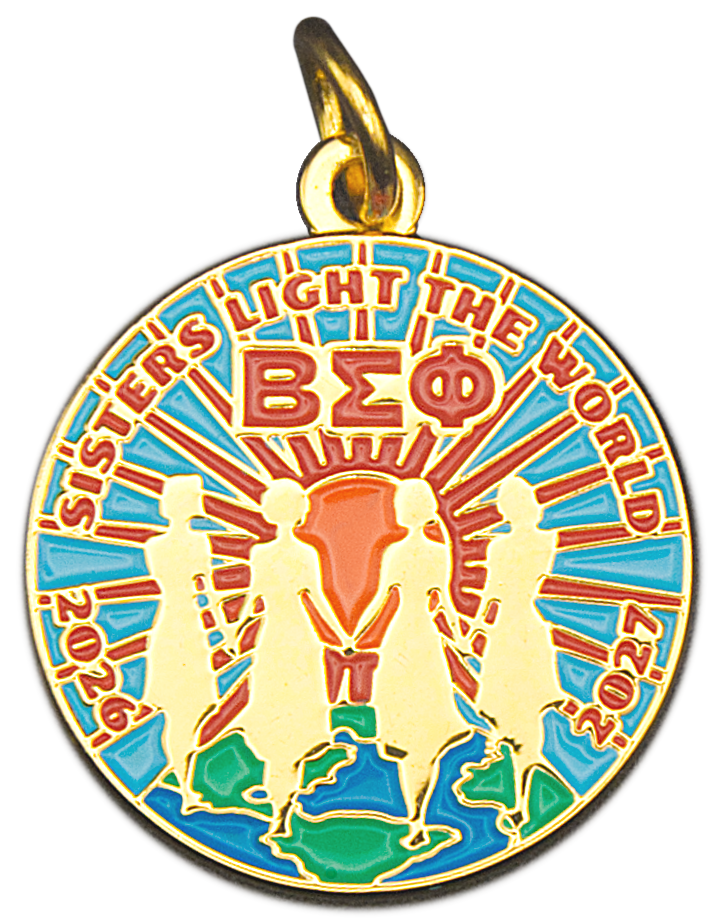 Gold and enamel commemorative charm of four women holding hands  before a sunset. 