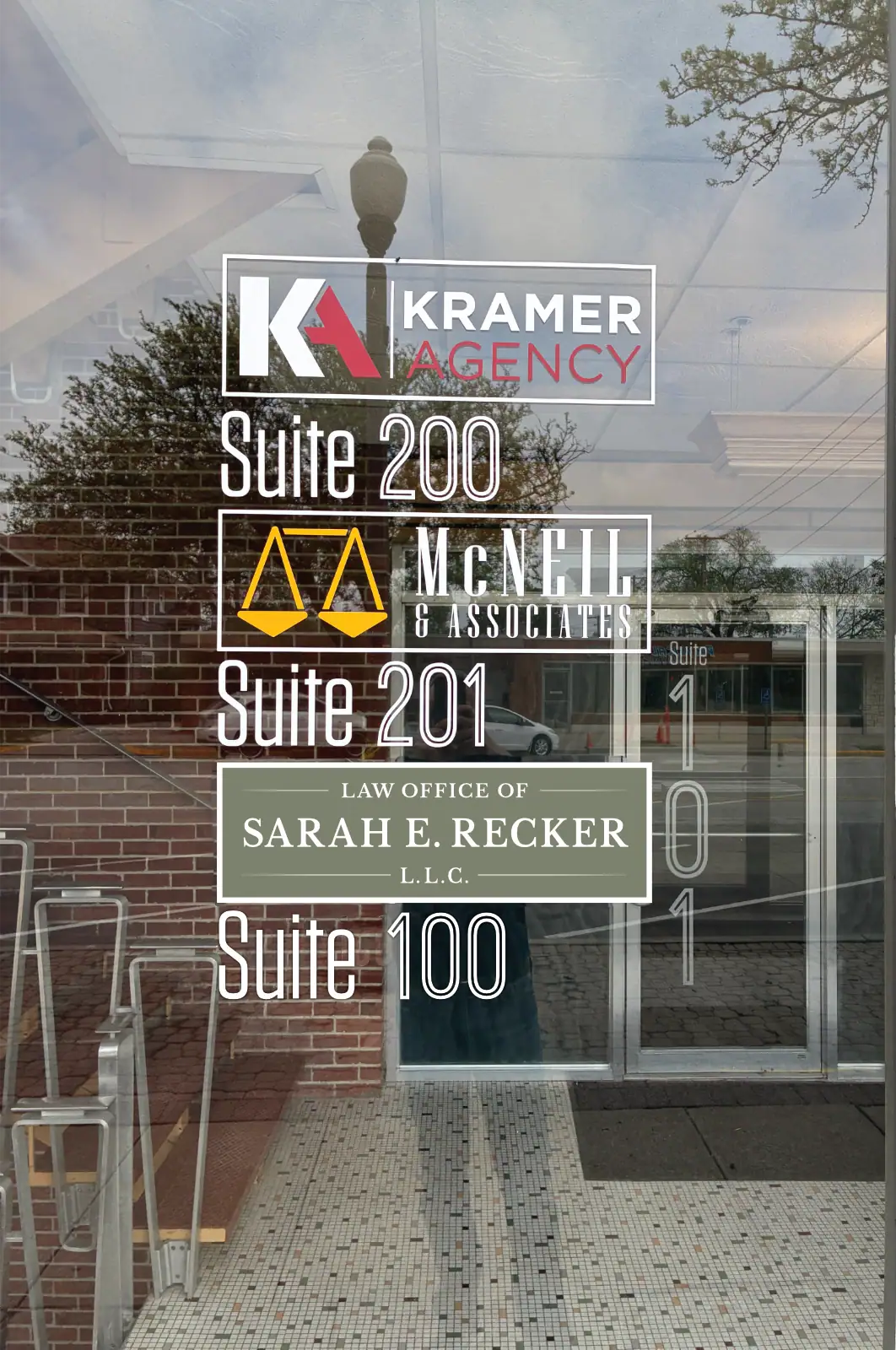Business office directory sign with suite numbers and law firm details on glass door.