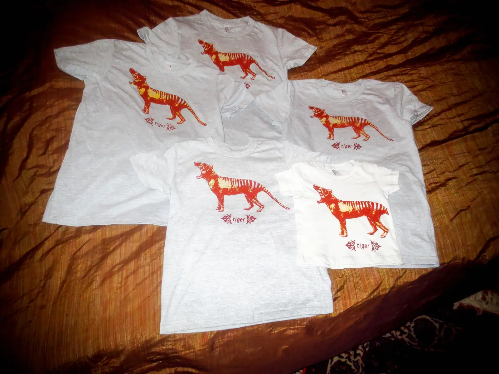 White T-shirts with orange tiger graphic and "Tiger Boy" text, laid on a wooden surface.